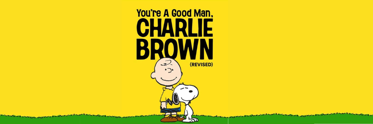 Graphic of a boy, Charlie Brown, wearing a collared shirt that is yellow and a black a zig zag design on the bottom of the shirt, black shorts, yellow socks, and brown shoes, with a white beagle, Snoopy, on green grass and a yellow background. Written in the middle You're a Good Man, Charlie Brown Revised.